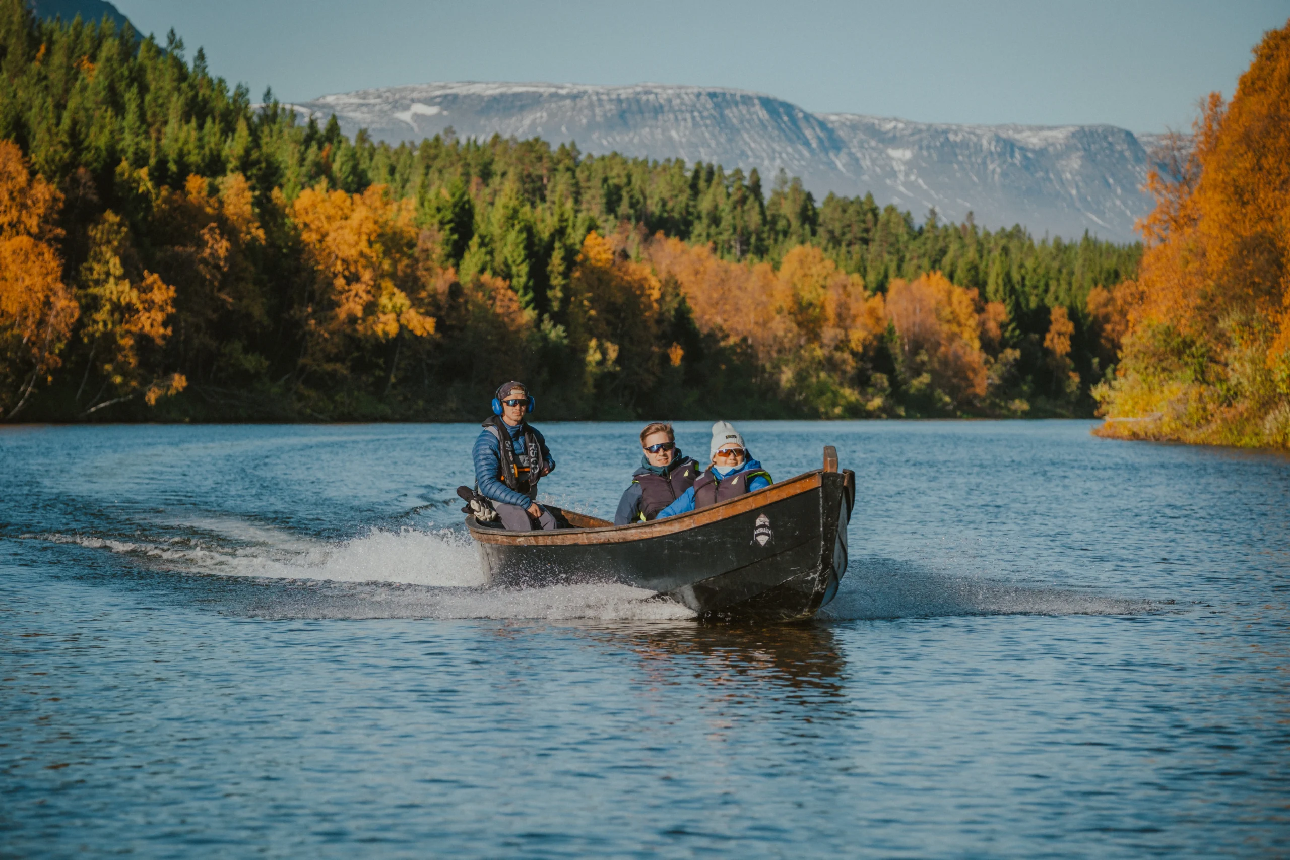 Traditional riverboat with passengers cruising the Reisa River in autumn, Reisa National Park